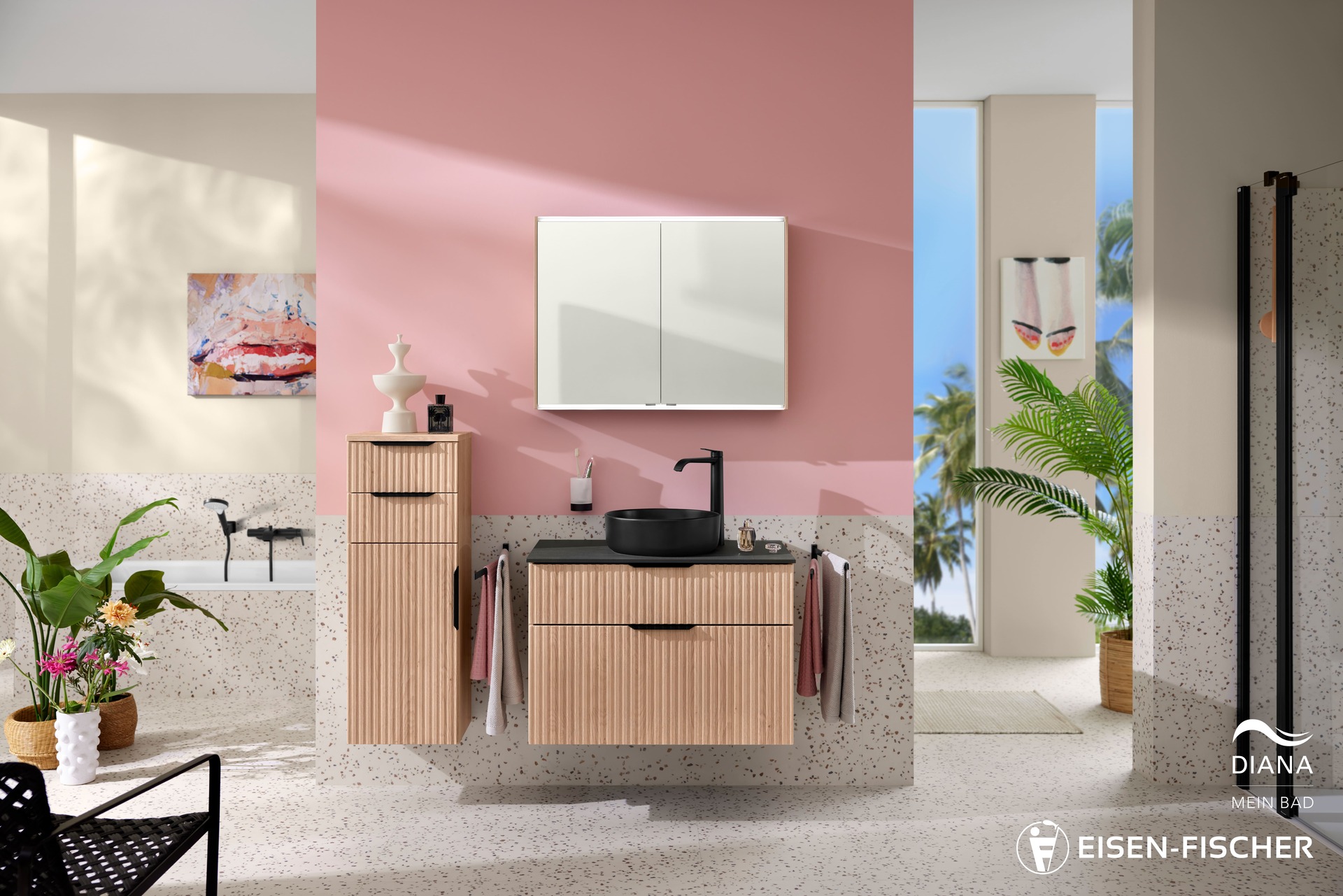 Badinstallation Ein modernes, vertikales Foto eines stilvollen Badezimmers mit pinkfarbenen und beigefarbenen Wänden. Im Zentrum steht ein Holzwaschtisch mit geriffelter Front und einer schwarzen Waschtischplatte. Darauf befindet sich eine schwarze, runde Aufsatzschale. Der Waschtisch ist an einer pinkfarbenen Wand montiert. Darüber hängt ein rechteckiger, weißer Spiegelschrank mit zwei Türen. Links davon steht ein schmaler, hölzerner Hochschrank, der ebenfalls an der Wand befestigt ist. Die Schränke gehören zur Marke "DIANA". Am unteren Rand des Bildes sind die Logos "DIANA - MEIN BAD" und "EISEN-FISCHER" zu sehen. Der Boden und der untere Teil der Wände sind mit beigefarbenen Terrazzo-Fliesen ausgelegt. Auf der linken Seite des Bildes ist eine freistehende Badewanne vor einer beigefarbenen Wand zu erkennen, an der ein modernes, abstraktes Gemälde hängt. Auf der rechten Seite sind eine Palme und ein Bild mit Schuhen vor einem Fenster mit Blick auf Palmen zu sehen. Die Beleuchtung ist hell und gleichmäßig.